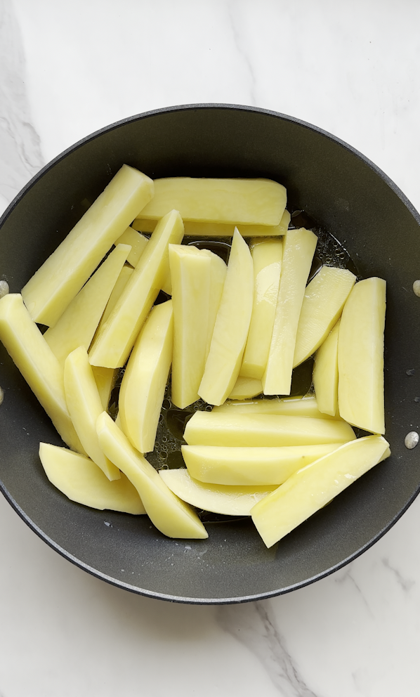 a pot full of cut up russet brand potatoes in a wedge style getting ready to cook